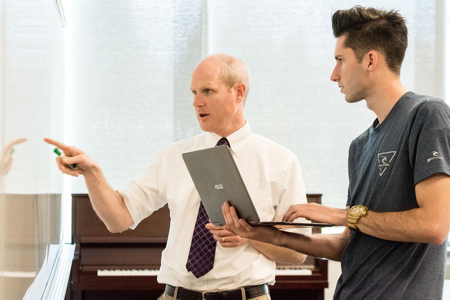 An instructor and a student talk through code on a laptop
