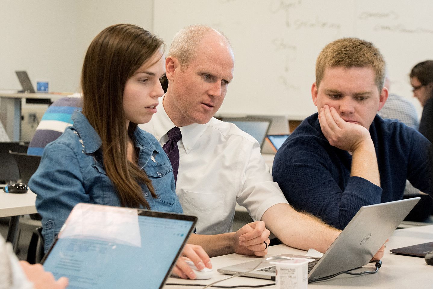 Students and an instructor work through a problem together on laptops